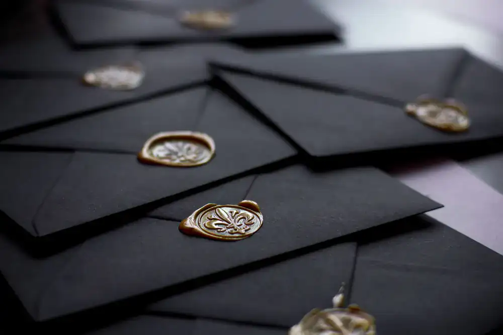 Stack of dark envelopes lettered with gold ink